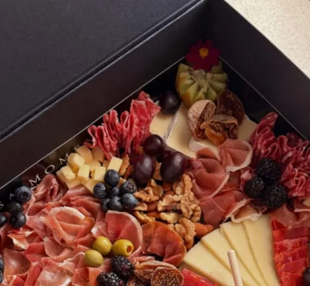 Caja Casa Momento abierta con jamón, quesos, frutos rojos y miel