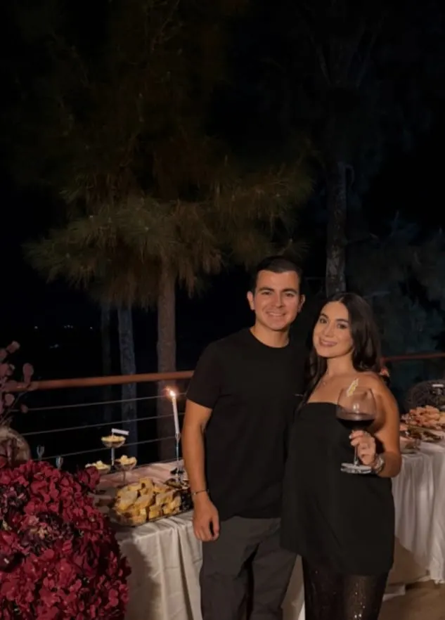 Gustavo y Pamela en el evento de lanzamiento, de noche, junto a la mesa de charcutería