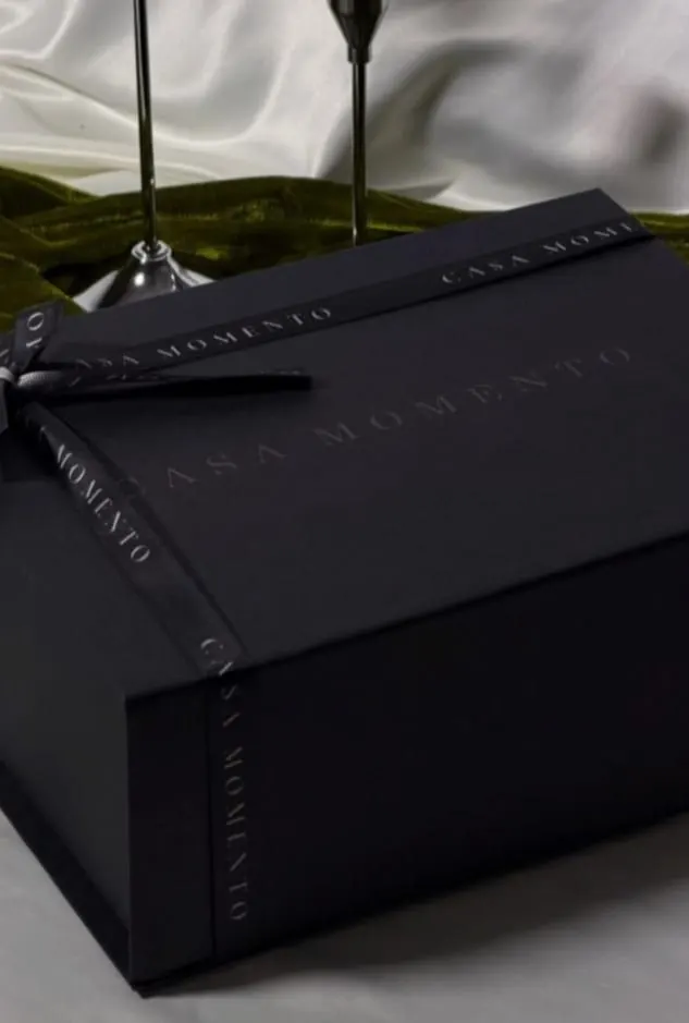 Caja Casa Momento con listón sobre tela blanca y terciopelo verde