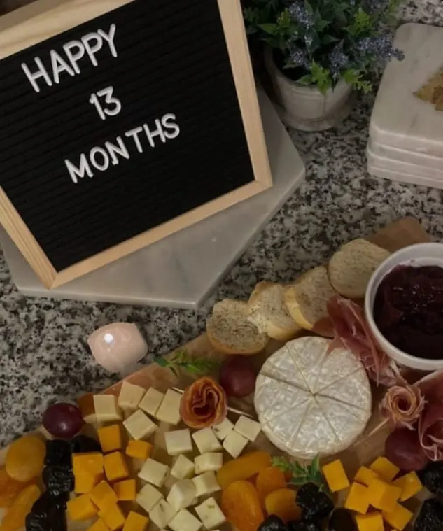 Tabla de charcutería en casa junto a un letrero de Happy 13 Months